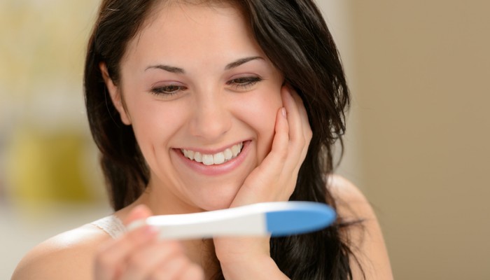 Delighted and surprised woman holding pregnancy test