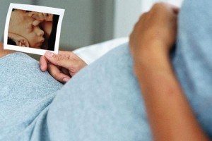 Беременная девушка держит в руках фото ребенка