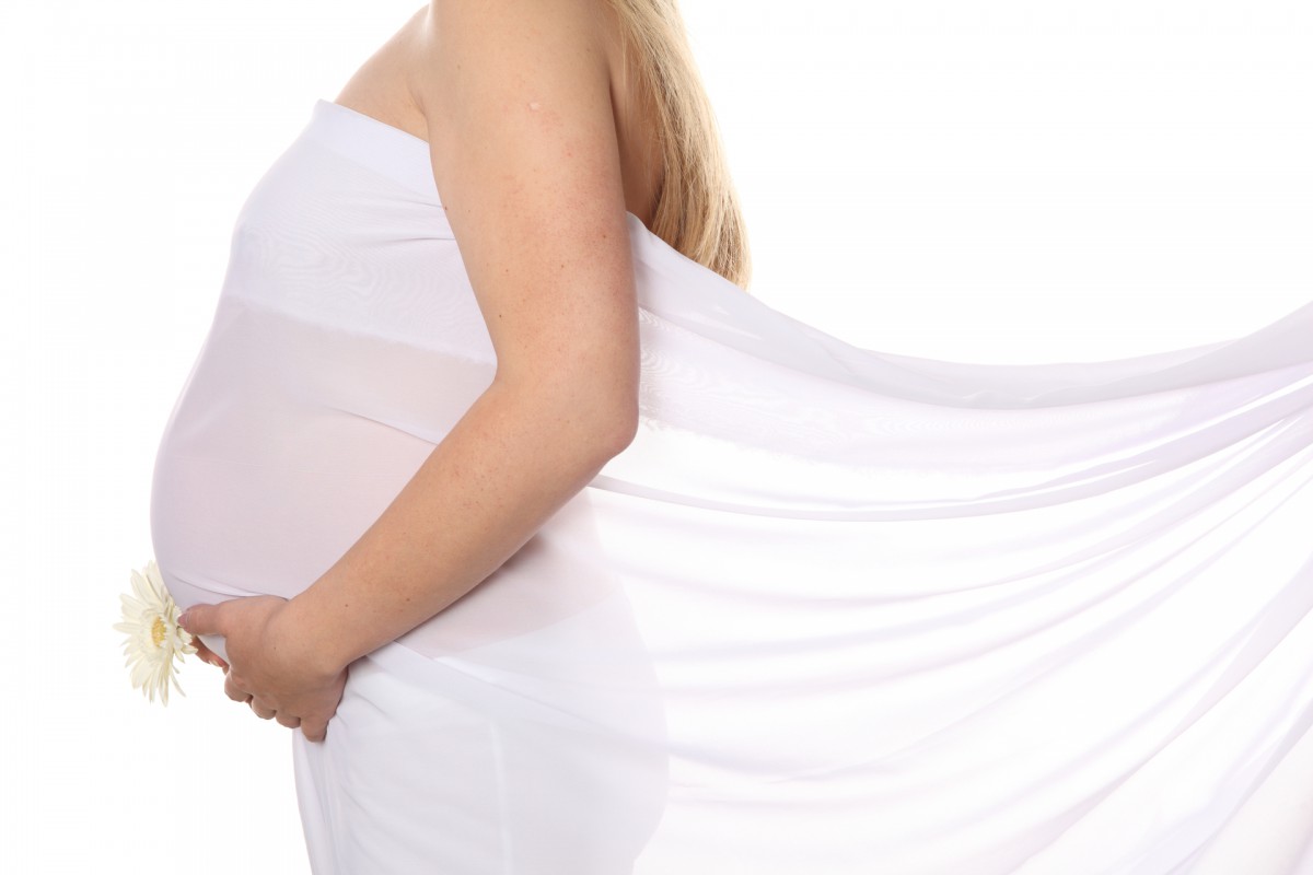 Беременная женщина стоит боком